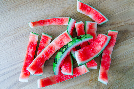 Fresh watermelon pieces are scattered on a wooden table after a summer picnic gathering