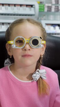 Young girl with a pigtail wearing a trial frame during a pediatric ophthalmology appointment. An optometrist is adjusting lenses to check her vision and prescribe new glasses for eyesight correction