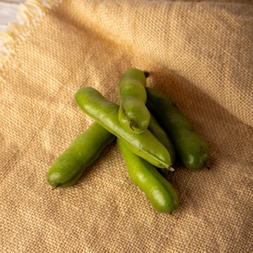Fresh fava bean pods on burlap fabric