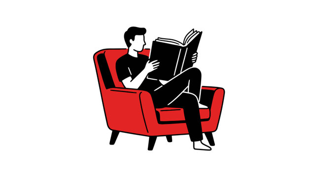 A young man sits in a comfortable red armchair while reading a large open book