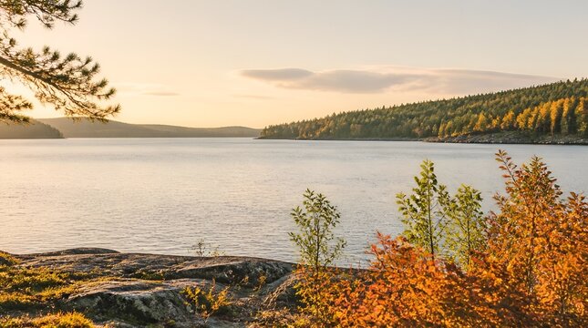 Scenic autumn landscape with a calm lake, rocky shore, and colorful foliage during golden hour sunset