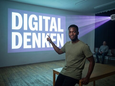 Junger Mann im olivgr&uuml;nen T-Shirt zeigt selbstbewusst auf projizierten Schriftzug Digital denken in einem Seminarraum