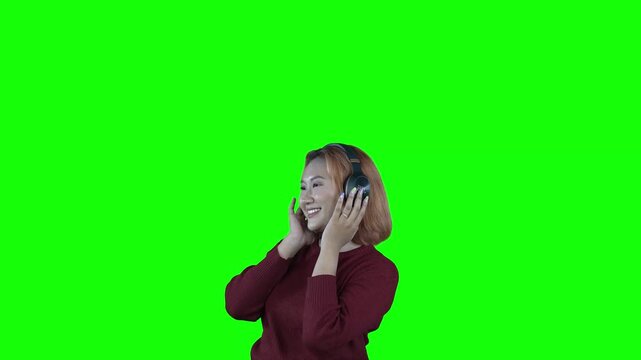 Happy Young Asian Woman Listening to Music on Headphones Isolated Green Screen