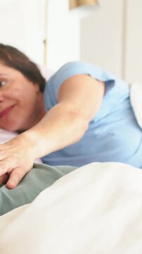 Vertical video: Seeking comfort, reaching woman in blue top touching hand on bed, smiling