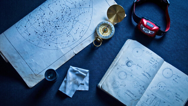 Astronomy observation kit star chart compass red lamp eyepiece on navy overhead, amateur astronomy kit concept, stargazing supplies flat lay, astronomy accessories overhead