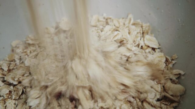 Close up of oats and dried berries mixed into a bowl for healthy granola breakfast