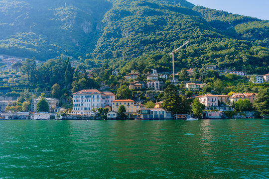 Scenic view of colorful lakeside villas along the shore of Lake Como, surrounded by lush green mountains in Carate Urio, Italy