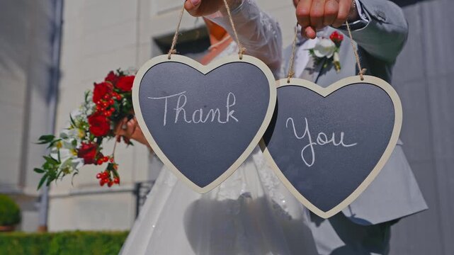 Bride and Groom Holding Thank You Heart Signs After Wedding Ceremony