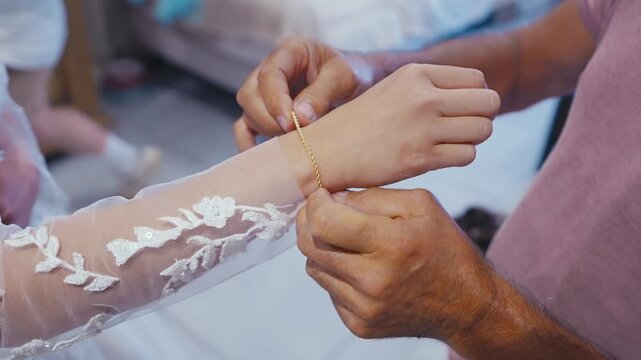 Close Up of Father Fastening Gold Bracelet on Bride Wrist