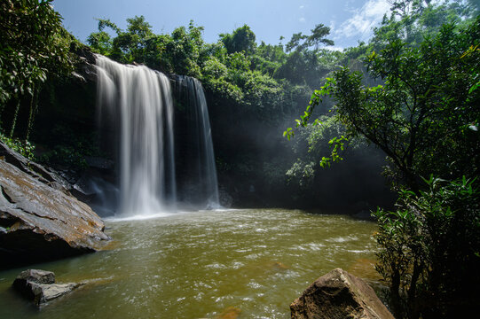 Scenic waterfall flowing into river surrounded by lush green tropical forest