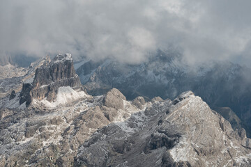A dramatic landscape featuring jagged mountain peaks dusted with snow and shrouded in thick, atmospheric mist. Ideal for travel and adventure themes. © marcodenaro