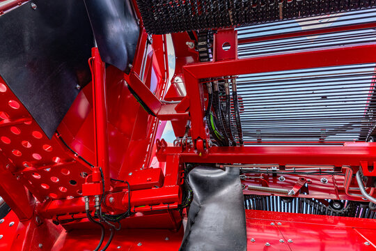 Agricultural machinery hydraulic lifting mechanism section. Modern farm equipment crop harvesting assembly with steel cylinders on red frame and industrial cultivation vehicle details view.