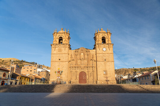 The impressive Baroque stone facade and twin bell towers of Puno Cathedral dominating the main square under a clear blue sky in Puno, Peru