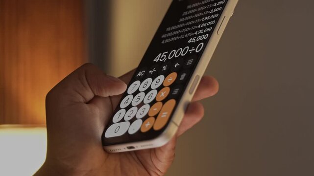 Hand Using Calculator App on Smartphone for Calculation.
