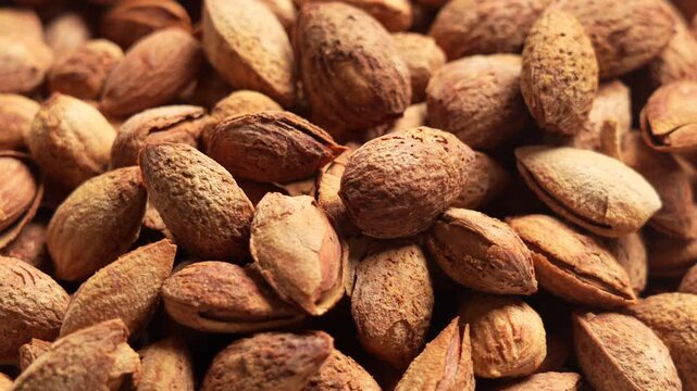 Close-up of roasted almond kernels with cracked shells, rustic texture for healthy snack or baking ingredient