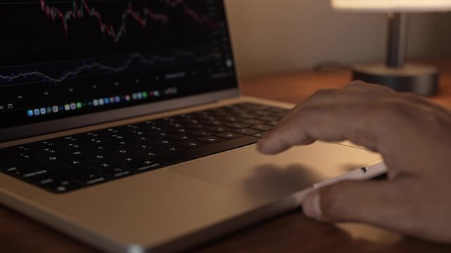Hand Using Laptop Trackpad in Warm Cozy Lighted Room.
