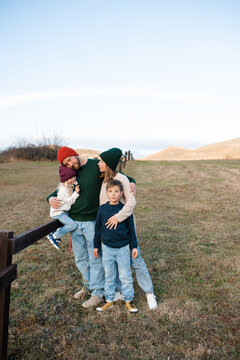 Happy family of mother, dad and children wearing knitted clothes in farmland. Autumn season.