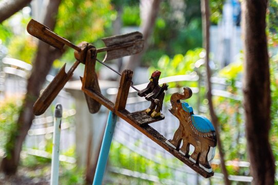 Traditional wooden wind spinner with carved elephant and rooster garden decoration 