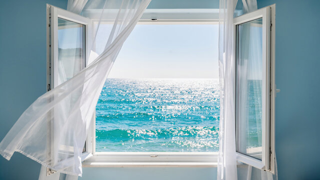 Open white window with sheer curtains and bright sparkling ocean view, concept for vacation, travel and coastal living