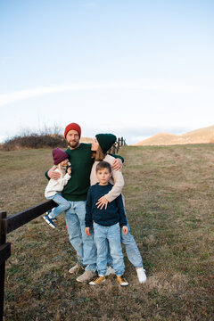 Happy family of mother, dad and children wearing knitted clothes in farmland. Autumn season.