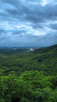 Aerial view of green Margalla Hills and Faisal Mosque under dramatic cloudy sky in Islamabad Pakistan