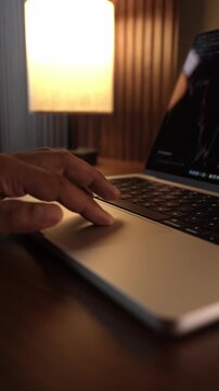 Hand Using Laptop Trackpad in Warm Cozy Lighted Room.

