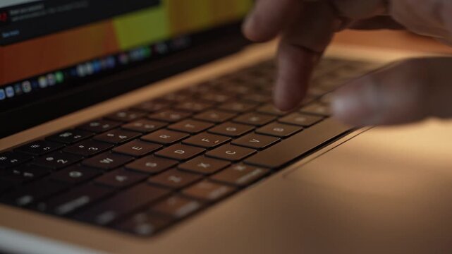 Hands Typing on Laptop Keyboard in Warm Cozy Lighted Room.
