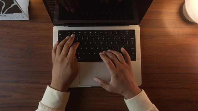 Hands Typing on Laptop Keyboard in Warm Cozy Lighted Room.
