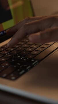 Hands Typing on Laptop Keyboard in Warm Cozy Lighted Room.
