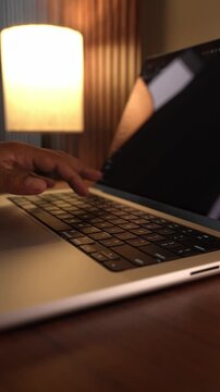 Hands Typing on Laptop Keyboard in Warm Cozy Lighted Room.
