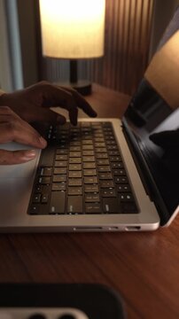 Hands Typing on Laptop Keyboard in Warm Cozy Lighted Room.
