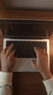 Hands Typing on Laptop Keyboard in Warm Cozy Lighted Room.
