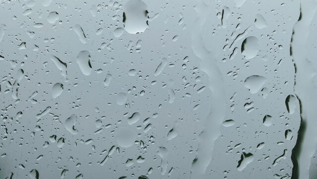 Water droplets on window glass with gray moody background in rainy weather