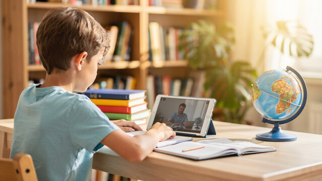 Young boy in light blue t-shirt engaged in online learning on a tablet with teacher, concept for education, e-learning and remote studying