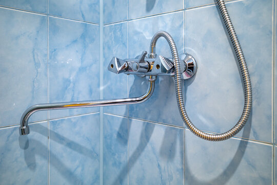 Modern chrome shower faucet on blue tiled wall