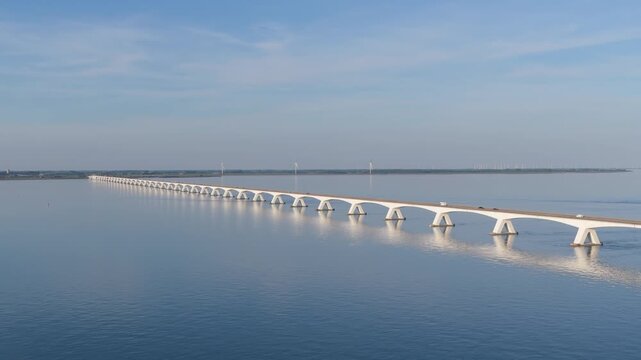 Aerial drone view of a long bridge crossing water in the Netherlands. Modern dutch transportation infrastructure and highway connecting coastal landscapes.