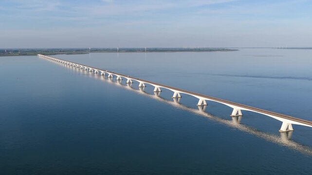Aerial drone view of a long bridge crossing water in the Netherlands. Modern dutch transportation infrastructure and highway connecting coastal landscapes.