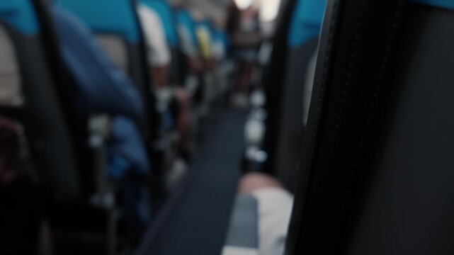 Blurred airplane cabin with passenger placing carry on luggage into overhead compartment before departure, commercial air travel, boarding process and modern aviation interior