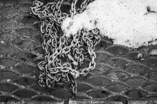 Heavy Metal Chain and Melting Snow on Industrial Grating Pattern