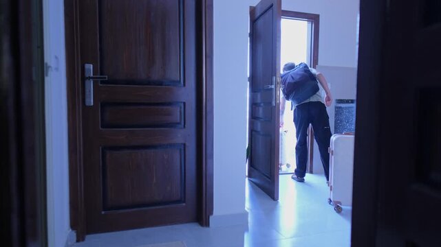 Young man leaving rented apartment with suitcases and backpack, moving out from temporary home, end of lease, relocation and housing transition concept