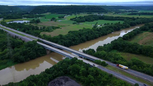 Flood water on Kentucky River with cars traveling across bridge over river as muddy water flows downstream after extreme rain weather event