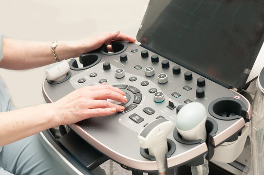 A close-up of an ultrasound machine. The doctor's hands are on the ultrasound machine's buttons.