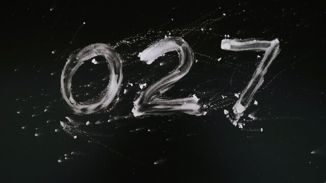 The number zero two seven 027 written in white chalk on a black chalkboard background.