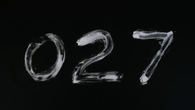 Handwritten number zero two seven 027 in white chalk on a black chalkboard background.