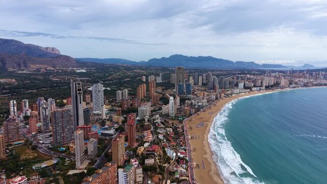 Aerial view of Benidorm, Spain, showcasing the iconic skyline of high-rise buildings along Levante Beach with turquoise Mediterranean waters and mountain backdrop
