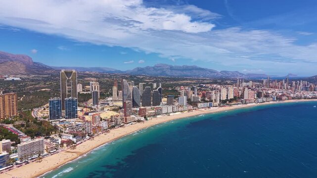 Aerial view of Benidorm city skyline along Playa de Poniente beach, turquoise Mediterranean Sea, high-rise buildings, and mountain backdrop, Alicante, Spain
