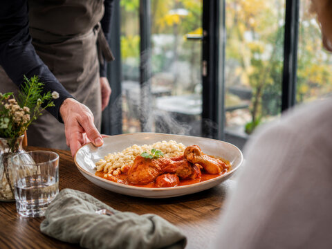 Servir un plato de paprikash de pollo con &ntilde;oquis en un restaurante en un d&iacute;a fresco