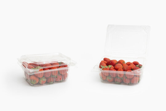 Fresh red strawberries in clear plastic clamshell packaging containers showing open and closed lid isolated on white background