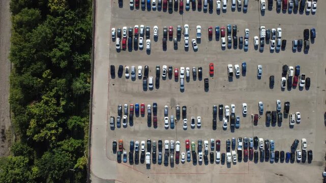 Geometric parking arrangements structure expanses of asphalt storage yards adjacent to natural green buffers highlighting efficient lot management. Vehicles maintain orderly alignment, Irving, TX