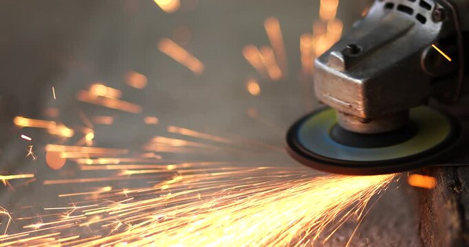 Worker using an angle grinder to cut metal with flying sparks. metalworking, industrial manufacturing, construction, fabrication, maintenance, engineering, and workshop concepts, close-up